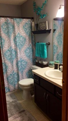 a bathroom with a toilet, sink and shower curtain in it's center area