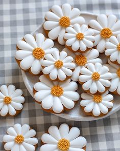 white and yellow decorated cookies in a bowl on a checkered tablecloth with daisies