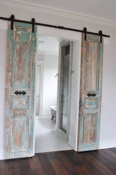 an open door leading to a bathroom with a tub in the background and wood flooring