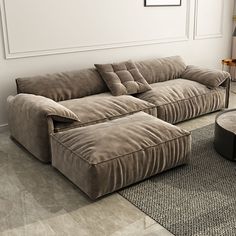 a couch and ottoman in a living room with a rug on the floor next to it