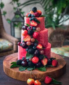 a watermelon cake with berries and cherries on the top is sitting on a wooden platter