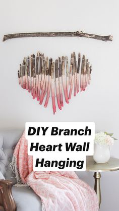 a white chair with a pink blanket on top of it next to a wooden heart shaped wall decoration