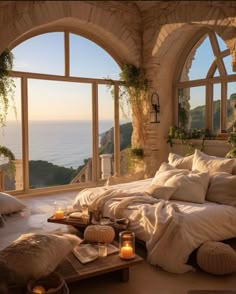 a bedroom with an arched window overlooking the ocean and candles in front of it,