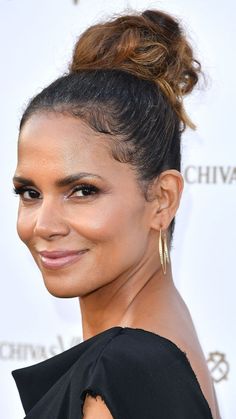 a close up of a person wearing a black dress with a bun in her hair