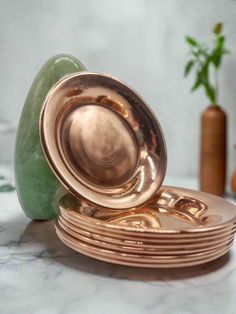 a stack of copper and green plates on a marble table