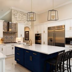 a large kitchen with white cabinets and blue island