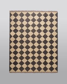 a black and white rug with an argyle pattern on the bottom, in front of a gray background