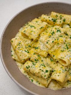 a bowl filled with ravioli and cheese on top of a white countertop next to a fork