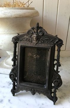 an old black frame sitting on top of a marble counter next to a potted plant