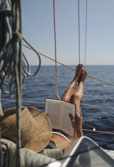 a person reading a book while sitting on a boat