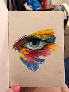 a person holding up a piece of paper with an eye painted on the inside of it