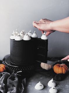 someone is decorating a black cake with white ghost decorations