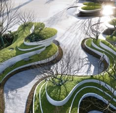 an aerial view of a park with green grass and small trees in the center, surrounded by concrete walkways