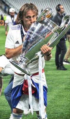 a man holding a trophy on top of a field