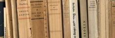 a row of books sitting on top of a wooden book shelf next to each other