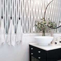 a bathroom with black and white wallpaper, two towels hanging on the hooks, a sink and a round mirror