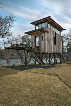 a small wooden structure sitting on top of a grass covered field next to a body of water