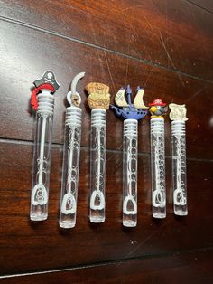 five glass pipes with different designs on them sitting on a wooden table next to each other