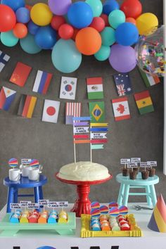 a table topped with a cake covered in frosting next to balloons and other decorations