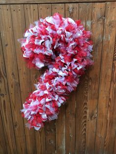 a red and white wreath hanging on the side of a wooden fence next to a wall