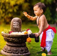 a little boy that is standing in front of a water fountain with flowers on it