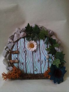 an image of a fairy door made out of wood and rocks with flowers on it