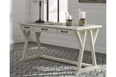 a white table with two drawers and candles on it in front of a window next to a rug