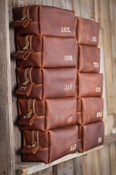 a wall mounted leather book case with initials on the front and back, hanging from a wooden