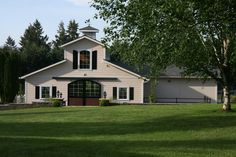 a white house with black shutters on the front and side windows is surrounded by green grass