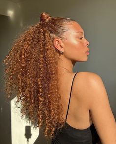 a woman with long curly hair standing in front of a mirror and looking off to the side