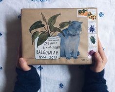 a person holding a brown paper bag with an image of a cat and plant on it