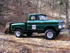 an old green truck parked in the woods