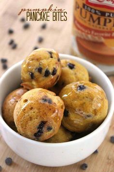 a white bowl filled with blueberry muffins next to a jar of pumpkin spice