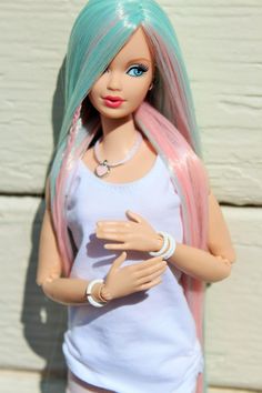 a doll with blue and pink hair standing next to a white brick wall wearing a bracelet