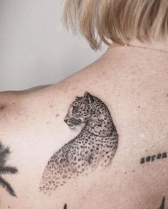 a woman's back with a cheetah tattoo on it