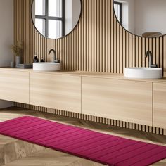 a bathroom with two sinks, mirrors and a pink rug on the floor in front of it