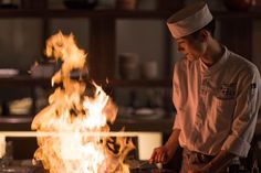 a chef is cooking on the grill with flames