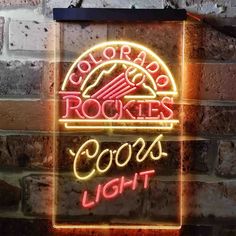 a neon sign that says colorado rockies coors light on the side of a brick wall