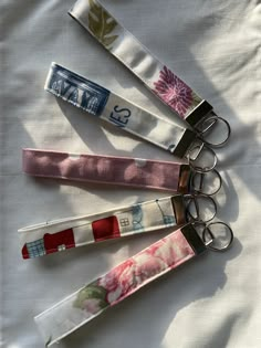 four keychains with different designs on them sitting on a white cloth covered surface