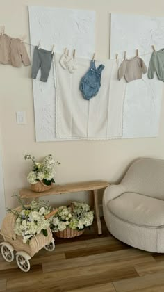 a baby's clothes line hangs on the wall next to a chair