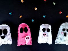 three little ghost puppets are lined up on a black surface