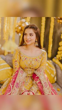 a woman in a yellow and red dress sitting on a bed with gold decorations around her