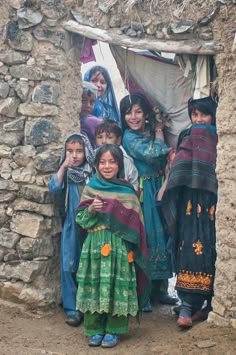 a group of people standing next to each other in front of a stone wall and doorway