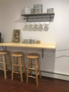 three wooden stools sitting on top of a counter next to a coffee cup dispenser