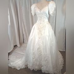 a white wedding dress on display in front of curtains