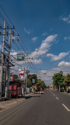 an empty street with lots of power lines and signs on the side of it,