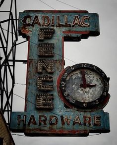 an old neon sign with a clock on it's side that says cadillac hardware