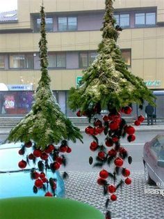 two christmas decorations hanging from the roof of a car in front of a city street