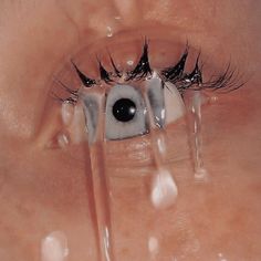 an eye with long black lashes and water drops on it