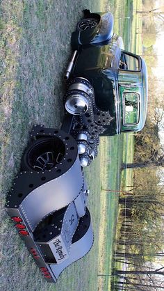 a motorcycle is parked in the grass next to a car that has been turned into a motorbike